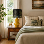 Load image into Gallery viewer, Rounded Gold ceramic table lamp beside a bed