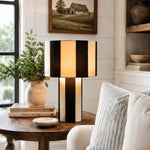 Cargar imagen en el visor de la Galería, Black and white striped woven table lamp lit on a wood side table
