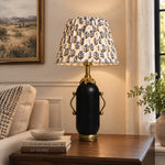 Bild in Gallery-Viewer laden, Matte black floral table lamp glowing on a dark side table