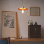 Charger l'image dans la visionneuse de galerie, Hand carved wood pendant light casting warm light on a quiet wall