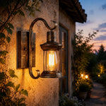 Load image into Gallery viewer, Antique bronze wall lantern glowing on an outdoor entry wall