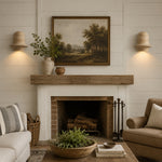 Cargar imagen en el visor de la Galería, Pair of travertine wall sconces installed beside framed art above a living room fireplace