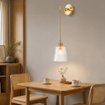 Bild in Gallery-Viewer laden, Brass and clear glass wall light installed beside a dining table