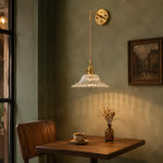 Bild in Gallery-Viewer laden, Brass and clear glass wall light in a calm living room corner