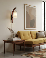 Cargar imagen en el visor de la Galería, Curved walnut and frosted glass plug-in wall lamp beside a lounge chair