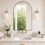 Cargar imagen en el visor de la Galería, Pair of chrome ribbed glass wall sconces around an arched bathroom mirror