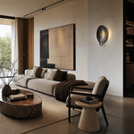 Load image into Gallery viewer, Black sculptural disc wall sconce in a modern living room