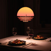 A table laden with delicacies appears all the more inviting beneath the warm, gradient glow of a Sunset Pendant Light, creating an intimate atmosphere.