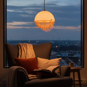 A person relaxing in a cozy reading nook defined by the low-hanging, warm Sunset Pendant Light.