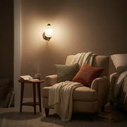 Cozy bedroom reading nook illuminated by a soft, warm, diffused Eloise wall sconce.