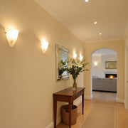 A bright, welcoming home hallway with wall sconces and a decorative mirror