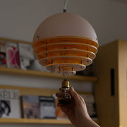 Person changing a burnt-out light bulb in a modern living room pendant fixture.
