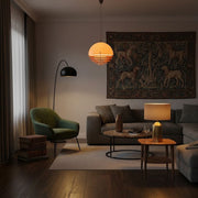 A modern living room featuring a Bauhaus Sunset Pendant Light layered with a warm floor lamp and a small table lamp on a side table.
