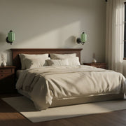 A cozy bedroom at night illuminated by warm milk glass wall sconces