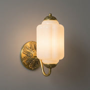 Eloise milk glass sconce with brass base casting a soft, creamy light in a home hallway.