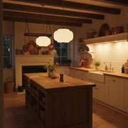 A warmly lit French country kitchen at dusk with layered lighting and a welcoming, gathered atmosphere