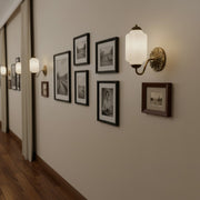 Hallway gallery wall illuminated by Eloise vintage milk glass sconces interspersed with framed art.
