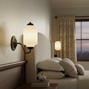 Soft warm light glowing from a vintage milk glass sconce in a cozy bedroom.