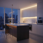 Modern kitchen featuring warm under cabinet LED strip lighting on marble countertops.
