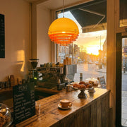 A warm sunset pendant light illuminating a modern industrial loft living room.