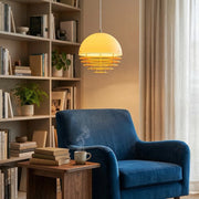 A cozy reading nook setup with a plush armchair and a Bauhaus sunset pendant light casting a warm glow.