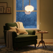 Eloise Scallop Vintage Milk Glass Pendant Light illuminating a cozy reading nook with snowy window in background.