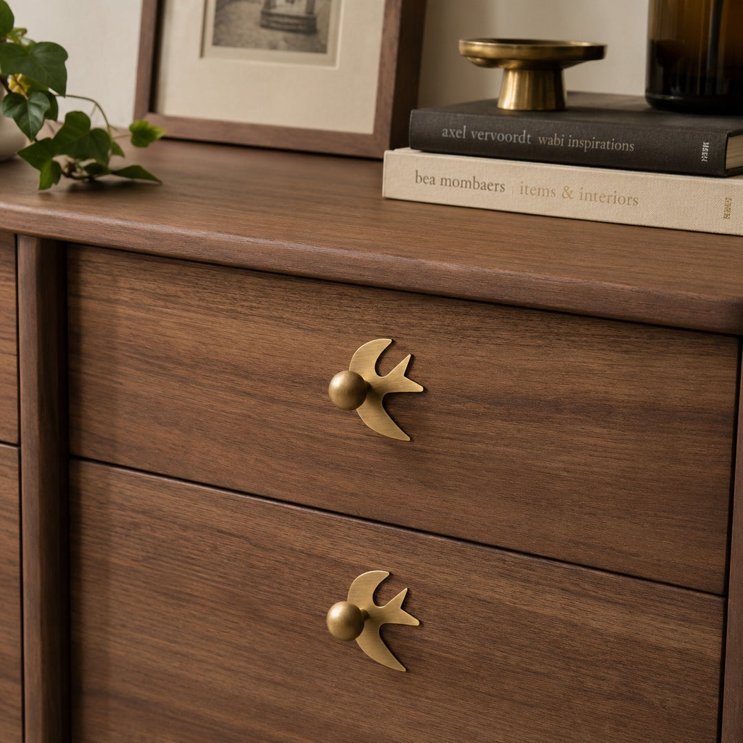 Swallow-shaped brass handles on wood drawers