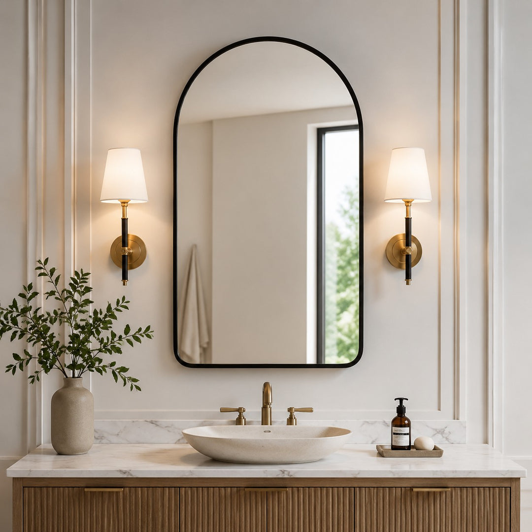 pair of natural brass wall sconces beside a vanity mirror
