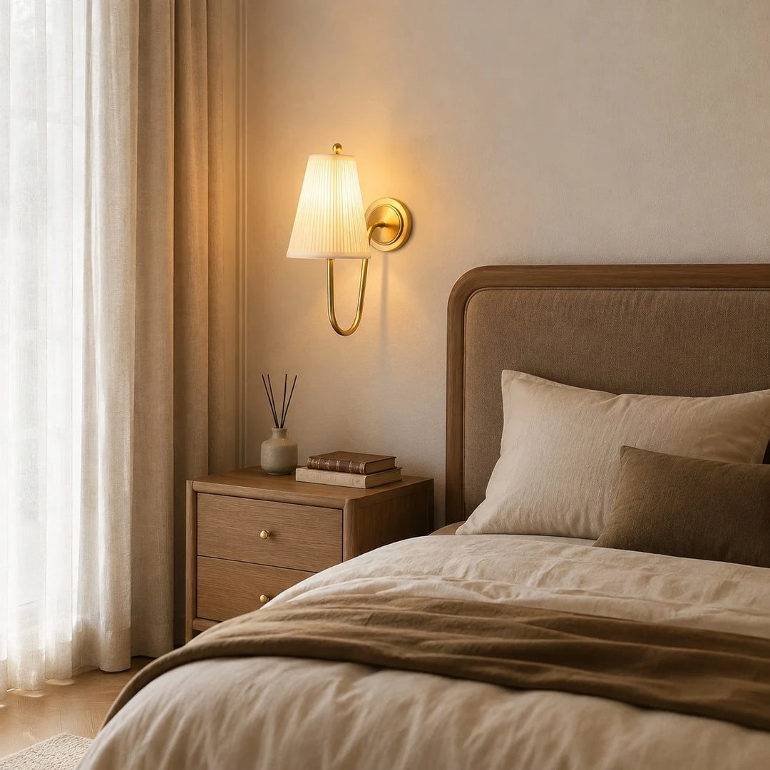 French brass fabric wall sconce installed beside a bed