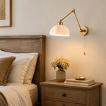 Load image into Gallery viewer, Gold wall lamp in a warm bedside setting