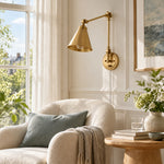 Load image into Gallery viewer, Gold swing-arm sconce beside a living-room chair