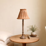 Load image into Gallery viewer, Warm tan pleated table lamp on small round bedside table