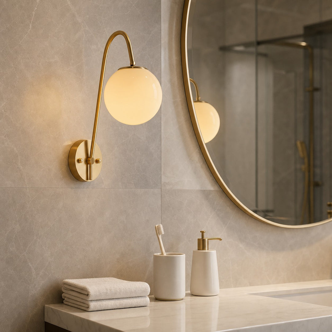 Brass globe wall light used beside a bathroom vanity mirror