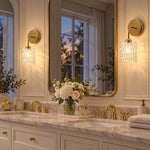 Cargar imagen en el visor de la Galería, Clear hammered-glass sconce on a marble vanity, lights on