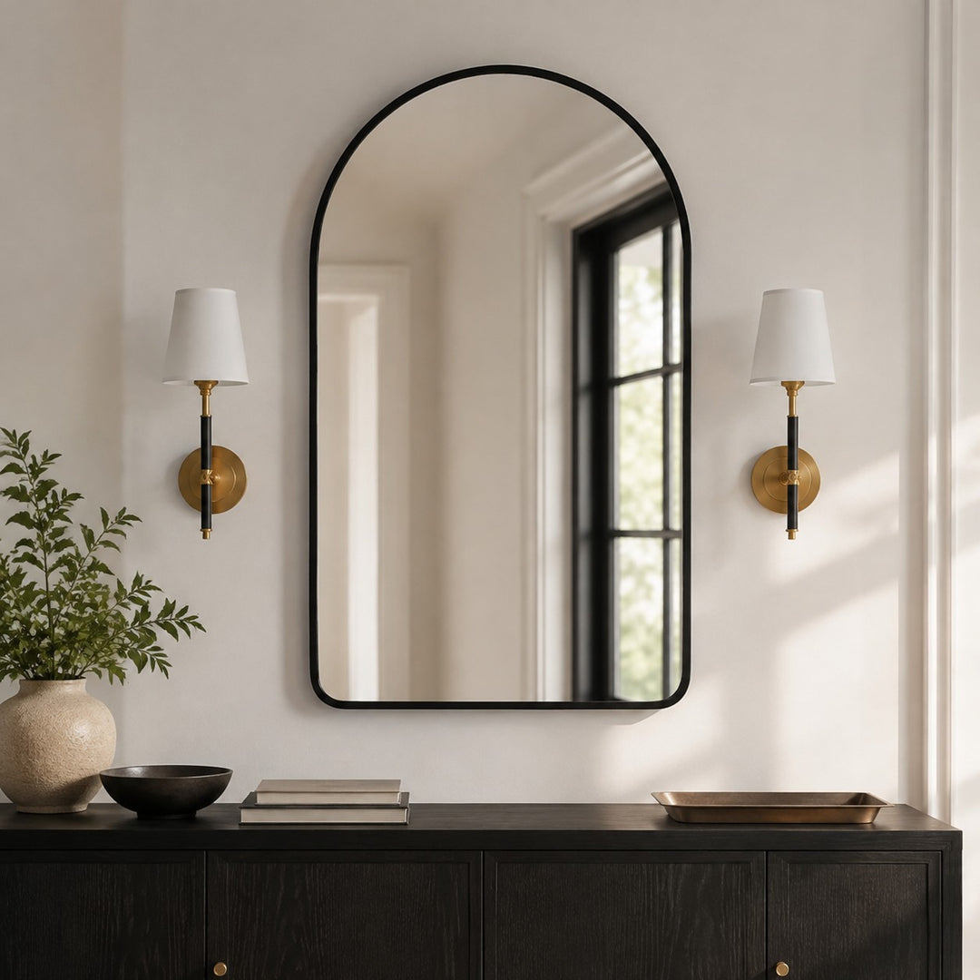 pair of natural brass leather wall sconces beside an arched mirror