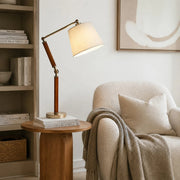 Adjustable wooden table lamp on a side table beside an armchair