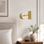 Load image into Gallery viewer, Brass cylinder wall sconce beside a neutral upholstered bed