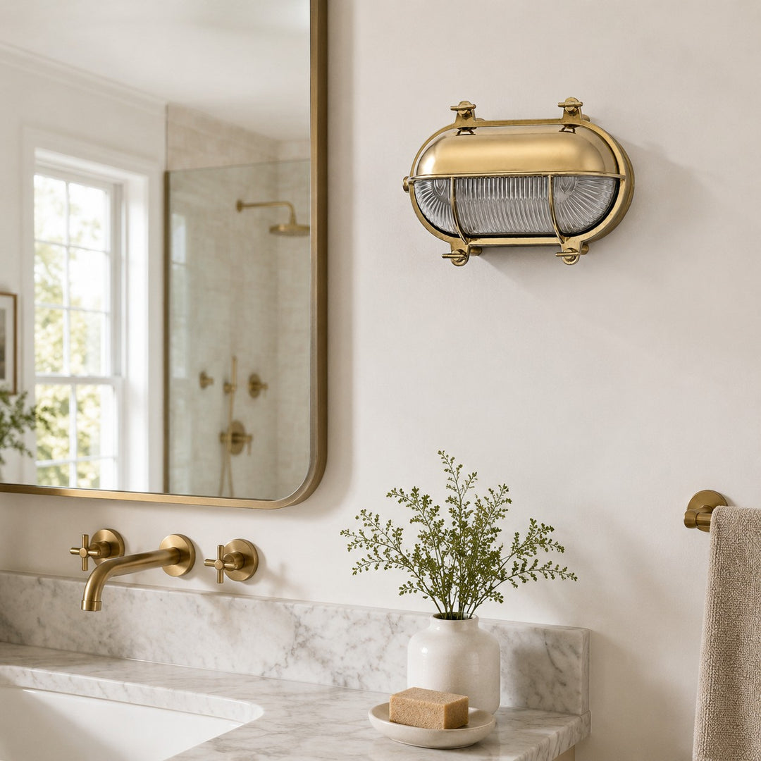 Aplique de pared Ivoran Bulkhead - Luz industrial vintage de vidrio con jaula de latón para exteriores y baño