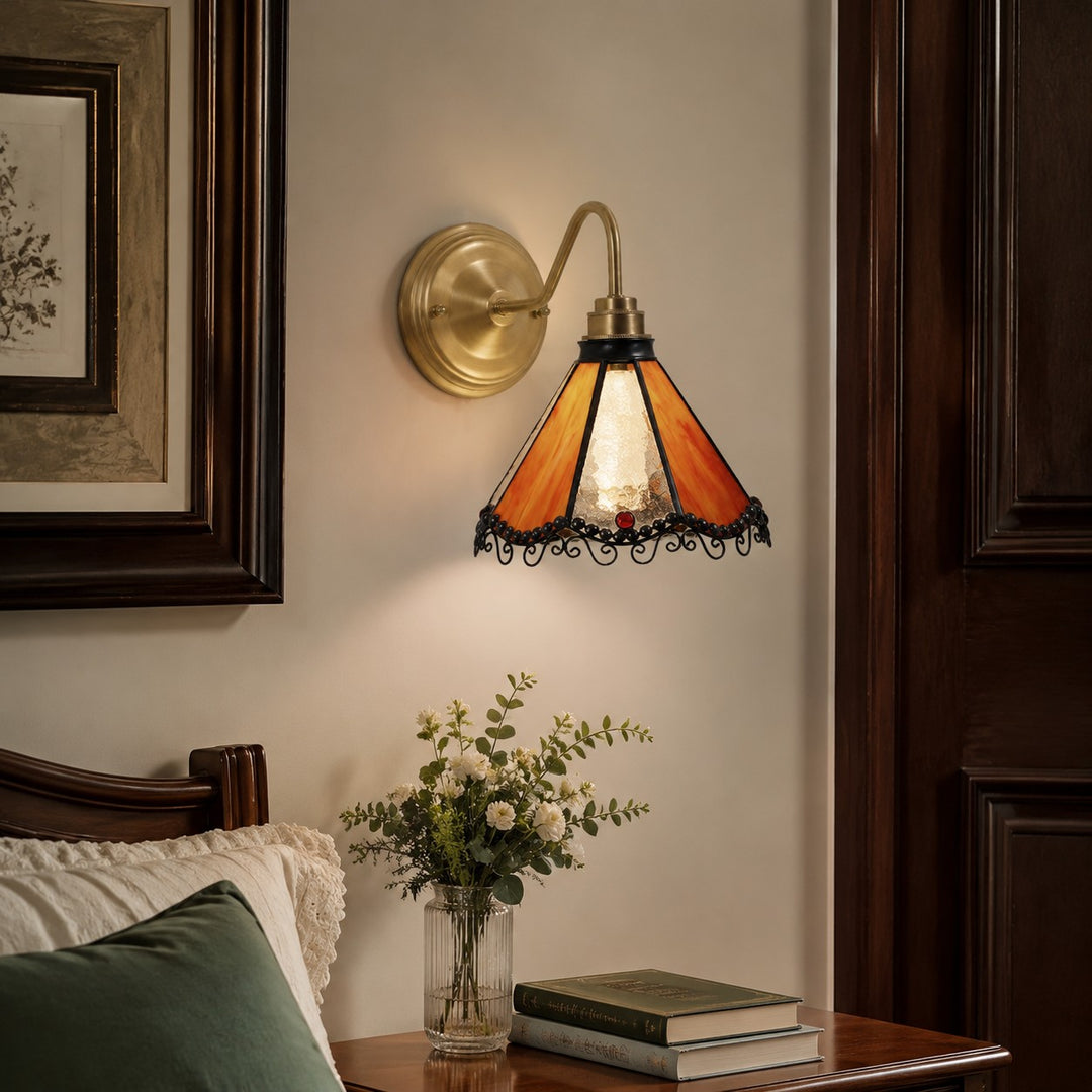 Orange stained glass wall sconce beside a vanity mirror