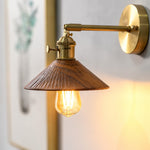 Load image into Gallery viewer, Wood and brass wall sconce casting warm light above a shelf