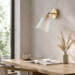 Bild in Gallery-Viewer laden, Brass and clear glass wall light beside a warm bedroom setting