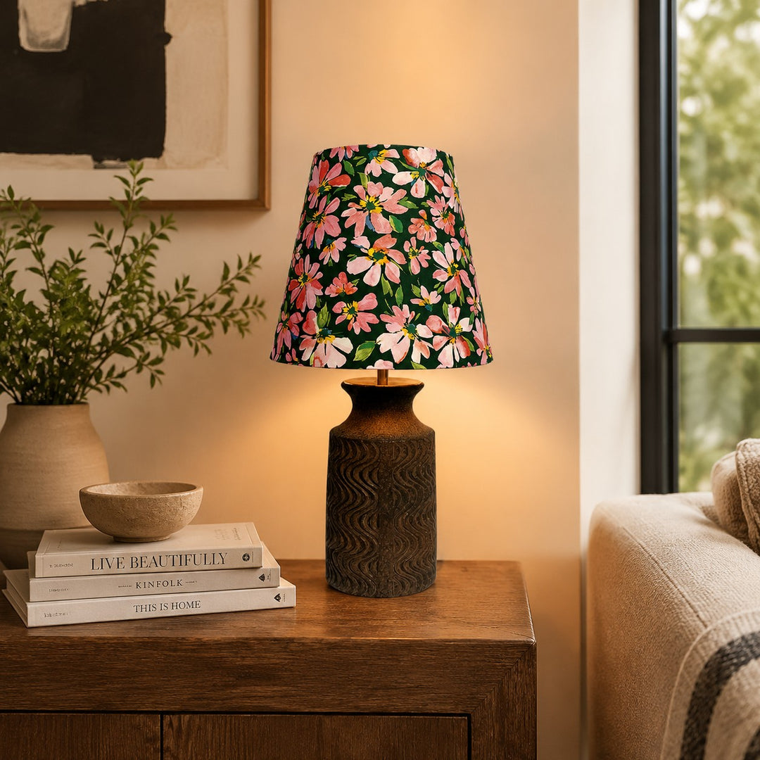 Floral ceramic table lamp glowing beside a sofa on a wooden side table