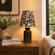 Floral ceramic table lamp glowing beside a sofa on a wooden side table