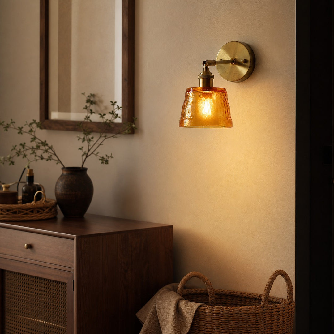 Amber brass glass wall sconce beside a mirror