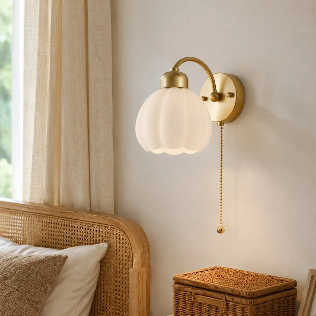 Pull-chain milk glass flower wall lamp beside a bed