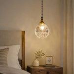 Load image into Gallery viewer, ribbed clear glass pendant light glowing over a bedside nightstand