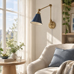 Load image into Gallery viewer, Blue cone shade on a gold swing arm beside a chair