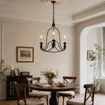 Load image into Gallery viewer, Black three-light candle chandelier above a round dining table