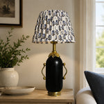 Load image into Gallery viewer, Matte black floral table lamp styled beside a green armchair