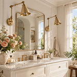 Load image into Gallery viewer, Two gold swing-arm sconces beside a bathroom mirror
